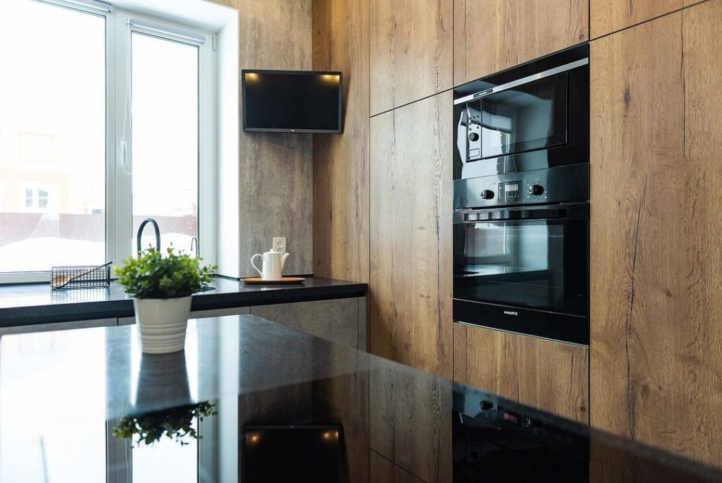 Кухня с древесной стеной шкафов и островом под бетон — ракурс 3