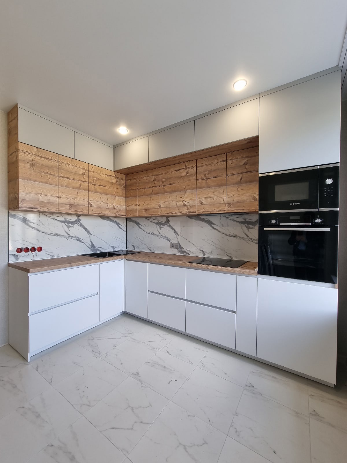 Угловая кухня с белым низом и выразительным древесным верхом — общий вид
